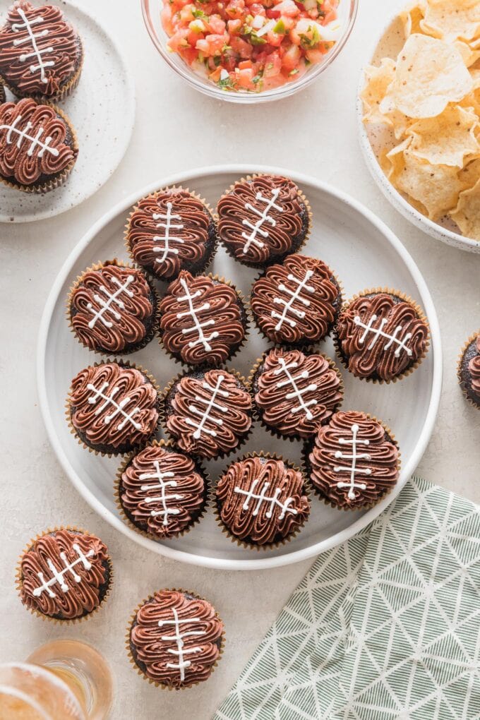 Platter of football cupcakes served for a tailgate party with chips, salsa, and frosty cold beer.