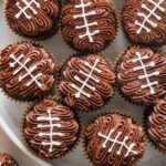 Overhead view of a large platter filled with decorated football cupcakes.