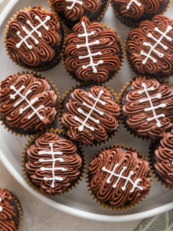 Overhead view of a large platter filled with decorated football cupcakes.