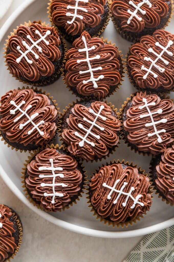 Overhead view of a large platter filled with decorated football cupcakes.