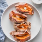 White platter holding four baked sweet potatoes.