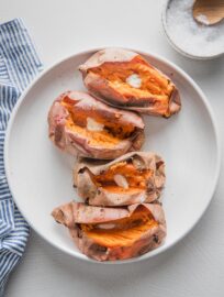 White platter holding four baked sweet potatoes.