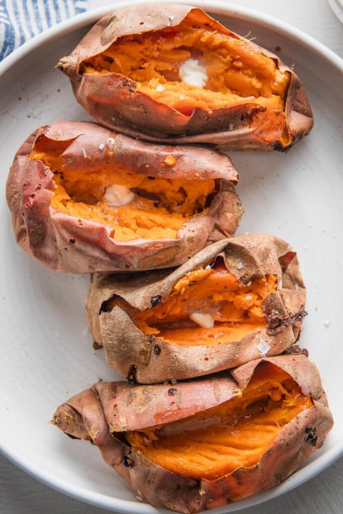 Close up of baked sweet potatoes split open and served with butter and sea salt.
