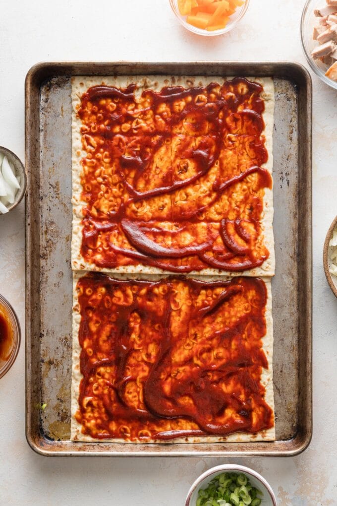 BBQ sauce spread out over two flatbreads.