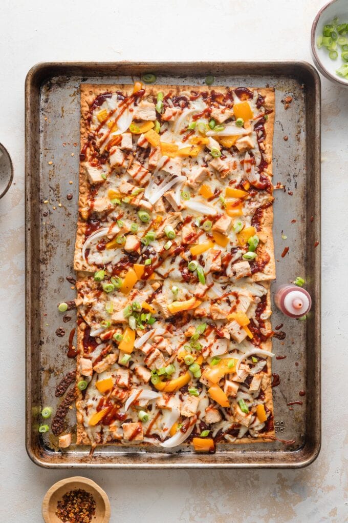 Baked BBQ chicken flatbread finished with an extra drizzle of BBQ sauce, green onions, and red pepper flakes.