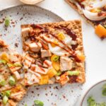 Close up of a BBQ chicken flatbread on a white plate.