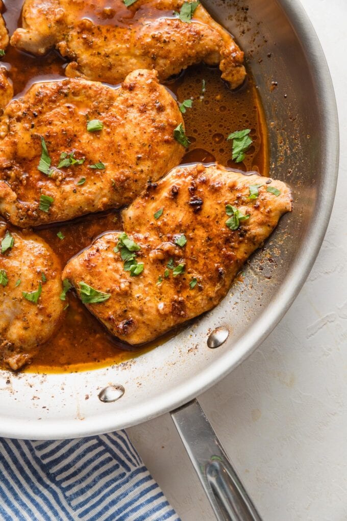 Skillet full of Cajun butter seasoned chicken breasts garnished with fresh parsley and ready to serve.