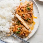 A thin-sliced chicken breast cooked with Cajun butter sauce and plated alongside white rice, with one slice cut to reveal a moist, tender interior.