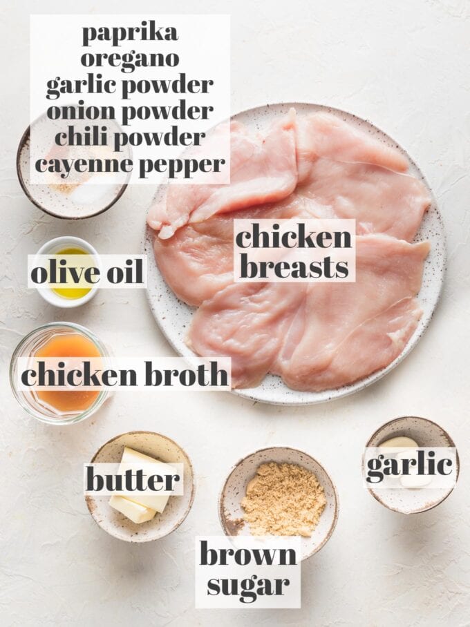 Labeled overhead photo of chicken breasts, spices, chicken broth, minced garlic, brown sugar, olive oil, and butter, measured into prep bowls and ready to cook.