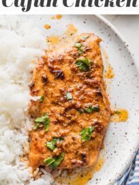 Cajun butter chicken breast with plenty of sauce, parsley for garnish, and a side of white rice on a white ceramic plate.