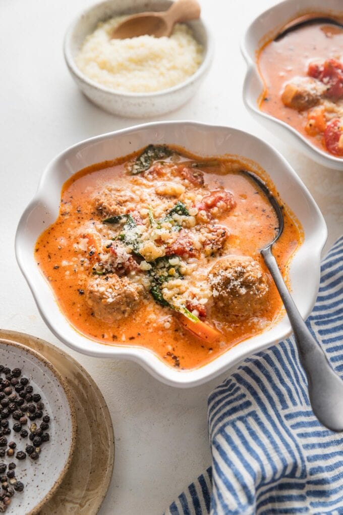 Angled view of creamy tomato meatball soup served in small bowls.