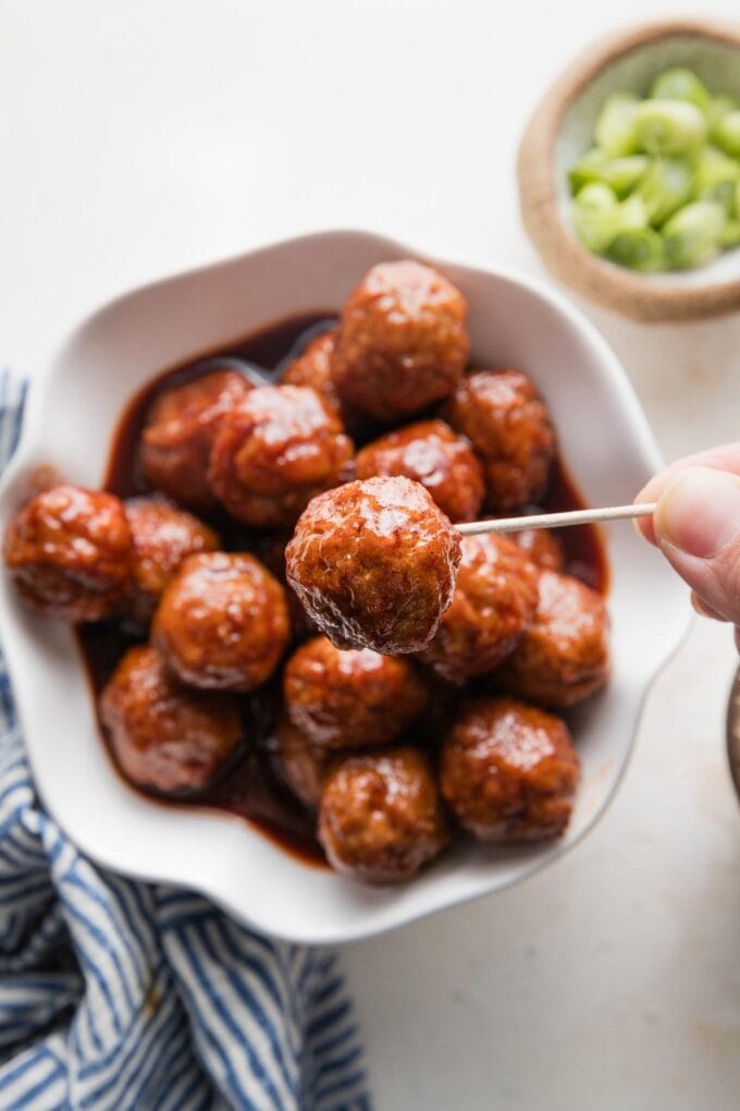 Mini BBQ meatball held up on a toothpick.