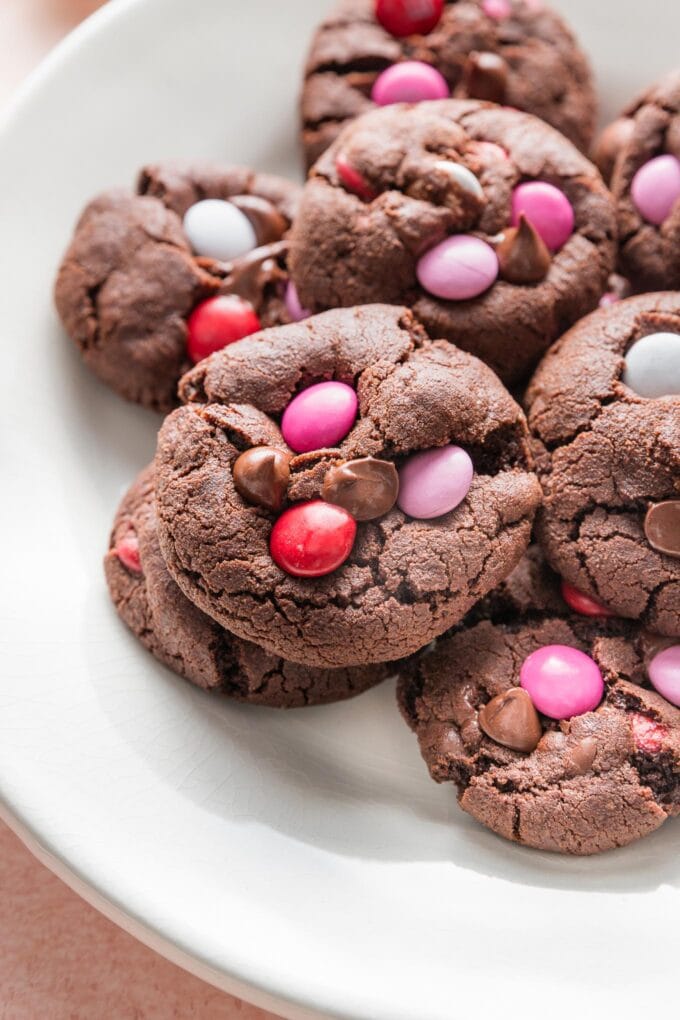 Close up of a double chocolate cookie with chocolate chips and Valentines-themed M&Ms.