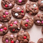 Pink countertop filled with rows of double chocolate Valentines cookies.
