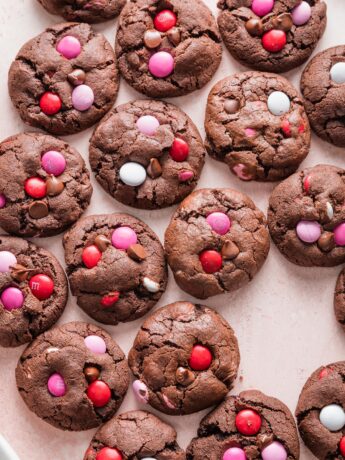 Pink countertop filled with rows of double chocolate Valentines cookies.
