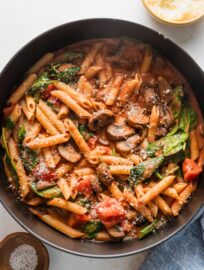 Cast iron skillet filled with a homemade penne rosa garnished with Parmesan.