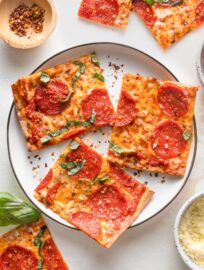 Small black-rimmed white plate with three pieces of pepperoni flatbread pizza.