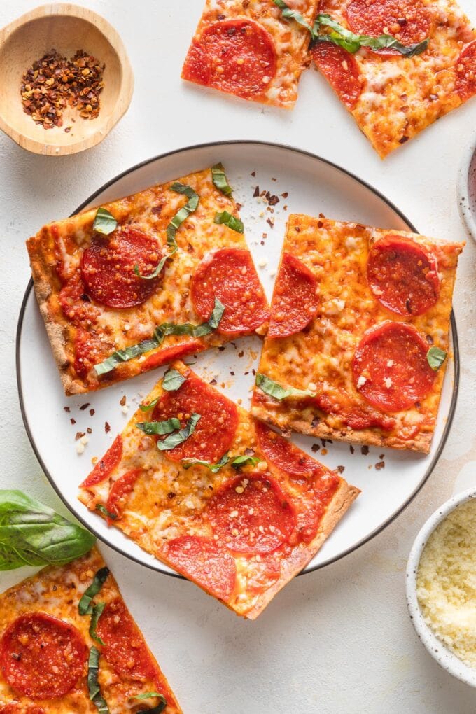 Small black-rimmed white plate with three pieces of pepperoni flatbread pizza.