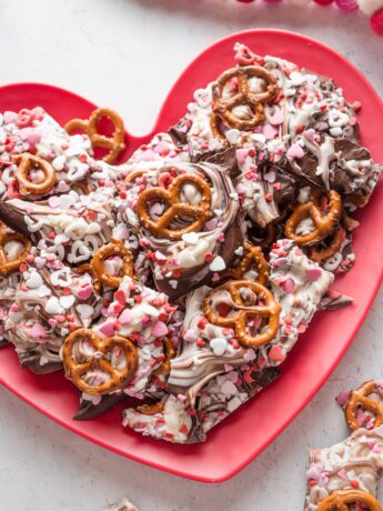 Chocolate pretzel bark with red and white heart sprinkled on a heart-shaped plate.