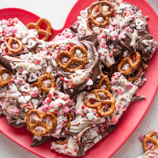 Chocolate pretzel bark with red and white heart sprinkled on a heart-shaped plate.