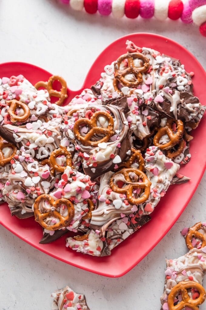 Chocolate pretzel bark with red and white heart sprinkled on a heart-shaped plate.