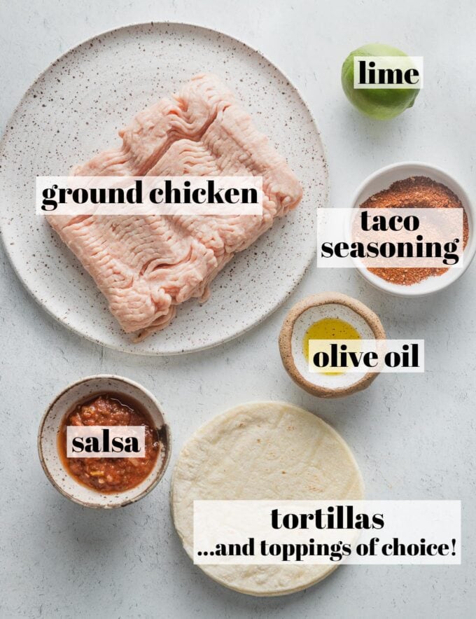 Labeled overhead photo of ground chicken, tortillas, taco seasoning, salsa, a lime, and olive oil, all in prep bowls and ready to cook.