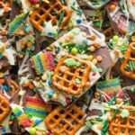 Close up of a piece of chocolate leprechaun bark with pretzels, sprinkles, and tart rainbow sours.