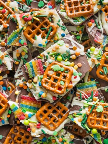 Close up of a piece of chocolate leprechaun bark with pretzels, sprinkles, and tart rainbow sours.