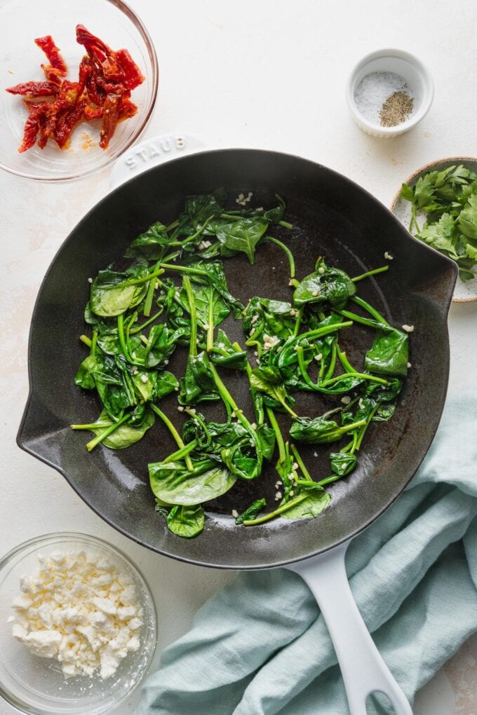 Baby spinach wilted in a cast iron skillet.