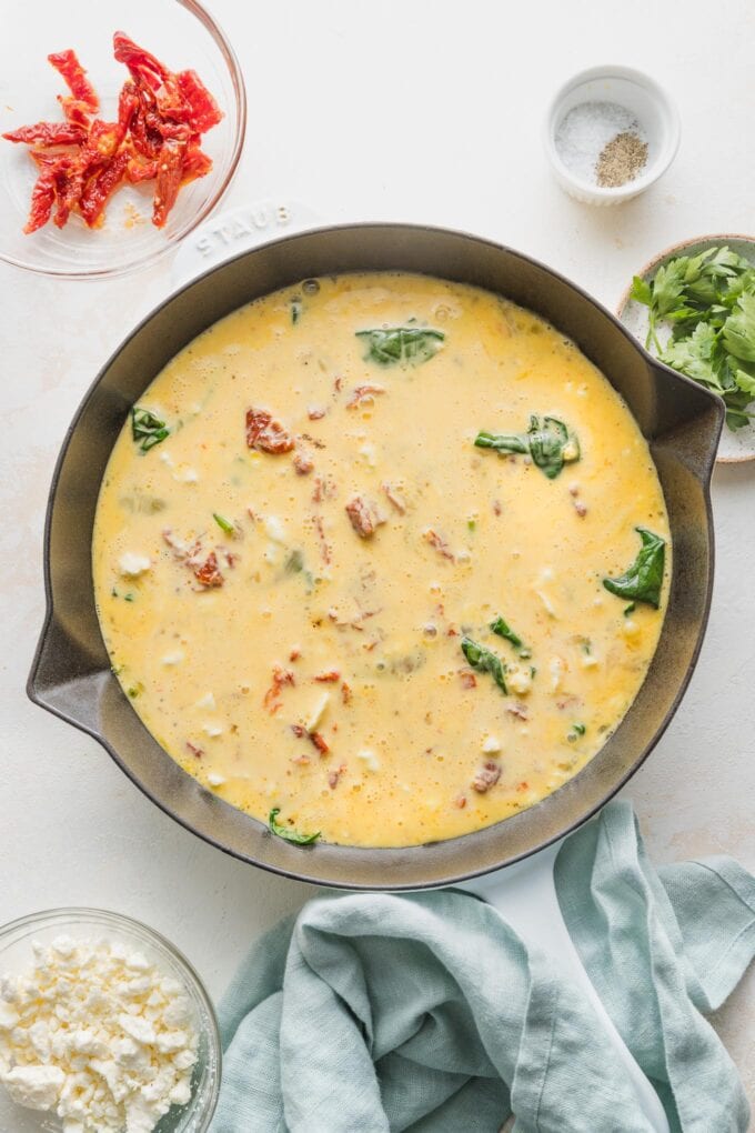 Egg mixture poured over spinach in skillet.