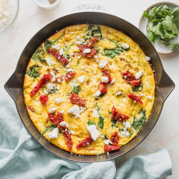 Overhead view of a Mediterranean frittata in a small cast iron skillet.