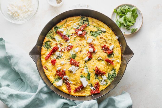 Landscape view of a Mediterranean-inspired frittata in a cast iron skillet.
