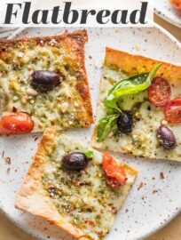 Crazy easy and packed with flavor, this Pesto Flatbread pizza has lots to love! We devour the fresh basil pesto, briny Kalamata olives, juicy tomatoes, and creamy mozzarella and Parmesan. And who doesn't enjoy a satisfying meal that takes just 5 minutes to toss together and 10 minutes to bake?