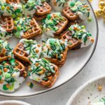 Angled view of St. Patrick's Day-themed Rolo pretzel candies stacked on a plate.