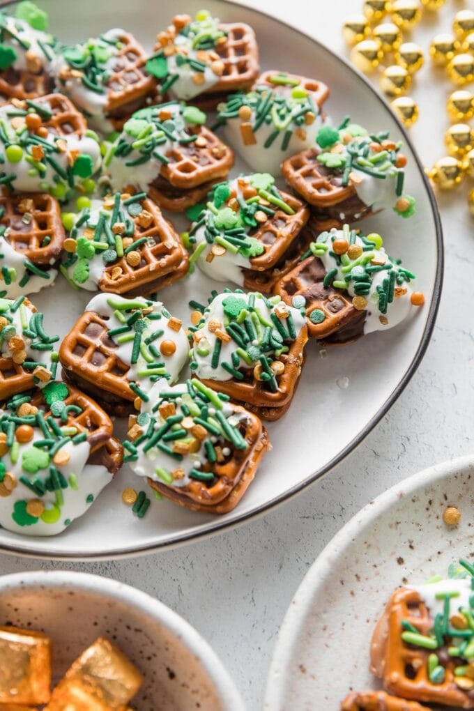 Angled view of St. Patrick's Day-themed Rolo pretzel candies stacked on a plate.