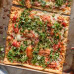 Two fully cooked BLT flatbreads on a sheet pan, just out of the oven and ready to slice and serve.