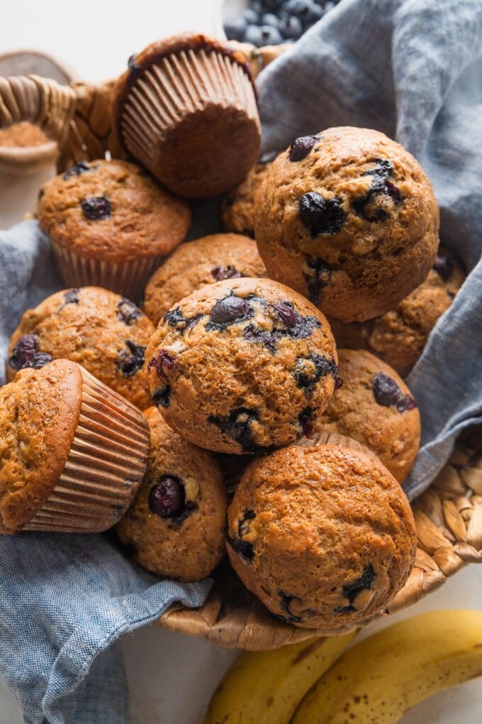 Bread basket lined with a blue kitchen cloth and filled with homemade banana blueberry muffins, fresh from the oven.