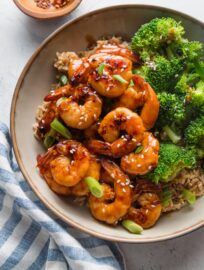 Countertop set with a bowl full of honey garlic shrimp, rice, and broccoli.