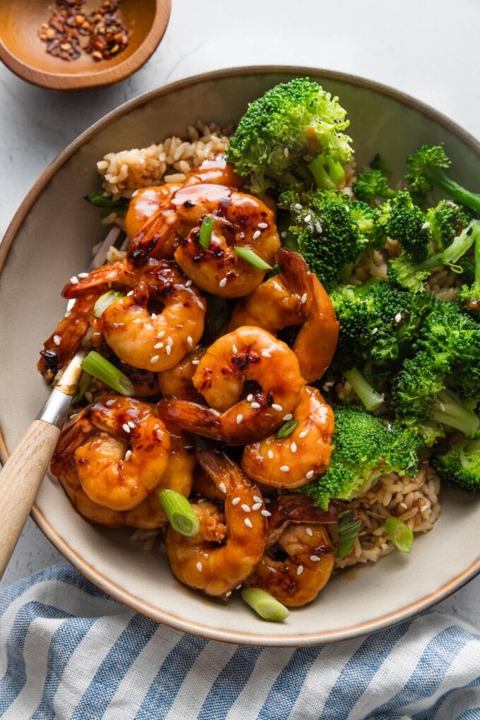 Close up of a bowl with honey garlic shrimp, steamed broccoli, and brown rice.