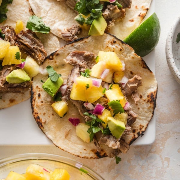 Close up of a carnitas taco with diced avocado and pineapple salsa.