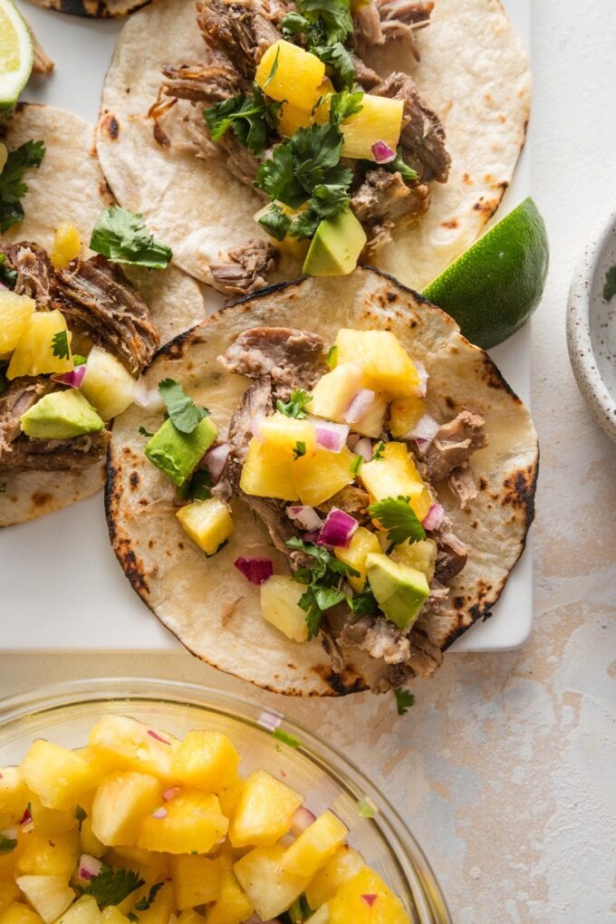 Close up of a carnitas taco with diced avocado and pineapple salsa.