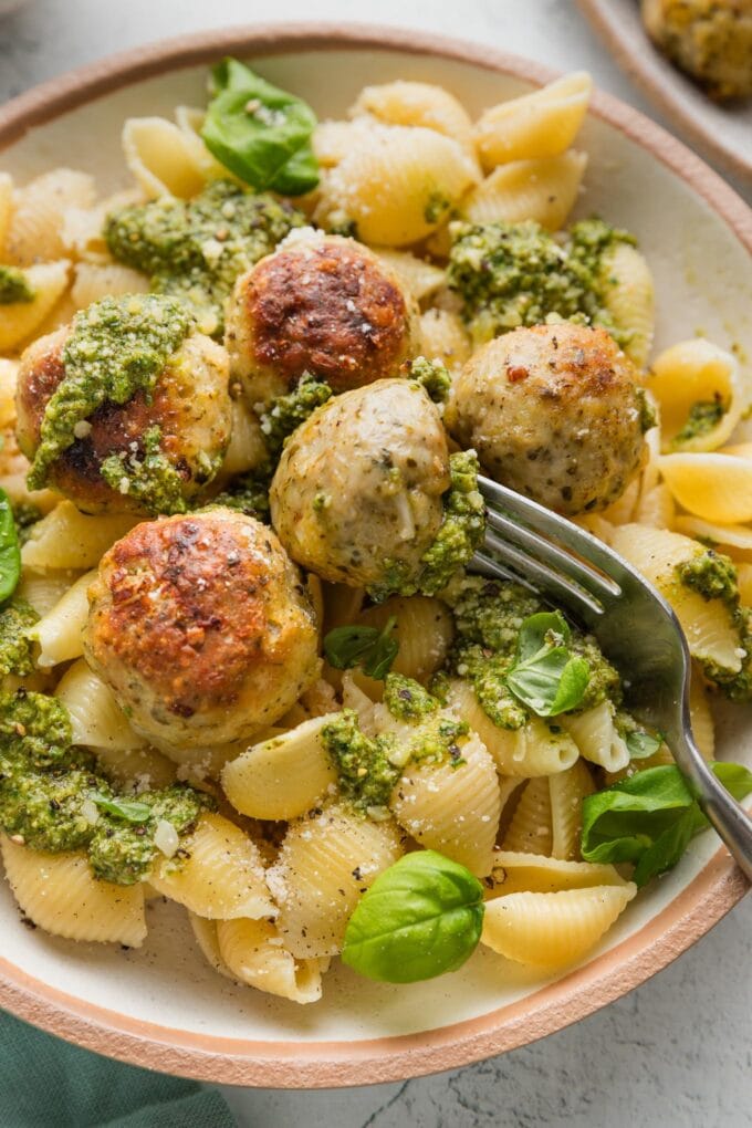 Fork holding up a small chicken pesto meatball.