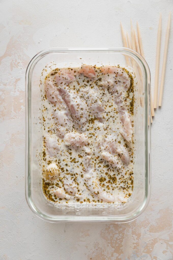 Chicken tenders marinating in a Greek-inspired yogurt sauce.