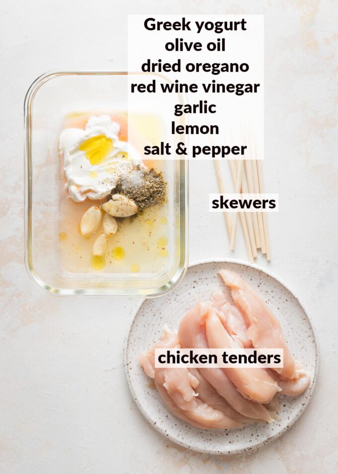Labeled overhead image of a Greek yogurt based marinade in a large tupperware with chicken tenders nearby ready to put inside.