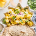 Pineapple salsa served with tortilla chips in a pineapple shaped serving dish.