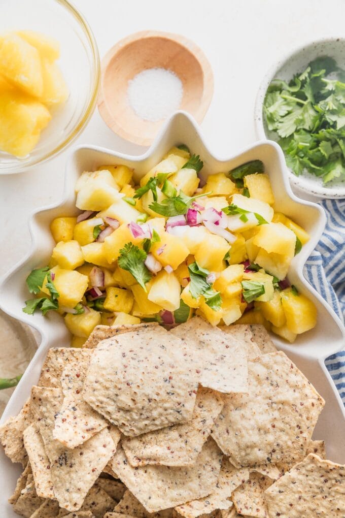 Pineapple salsa served with tortilla chips in a pineapple shaped serving dish.