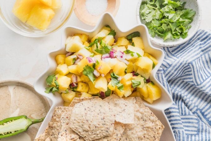 Pineapple-shaped serving dish full of tortilla chips and a fresh pineapple salsa.