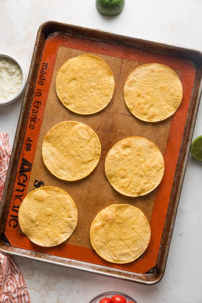 Six tostadas on a large rimmed baking sheet.