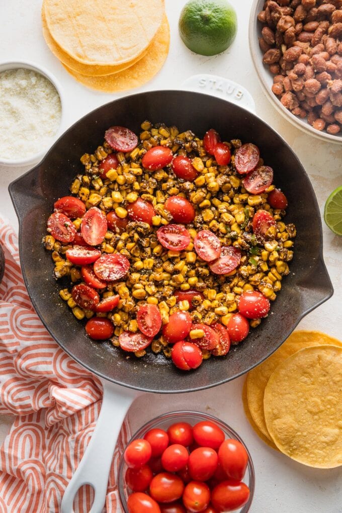 Cast iron skillet full of street corn tomato salsa with Cotija.