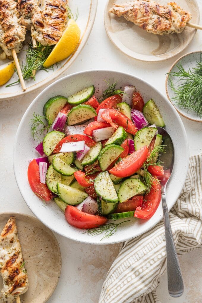 Bowl full of cucumber tomato salad with fresh dill, olive oil, and red wine vinegar for dressing.